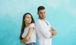 Couple standing back to back with arms crossed