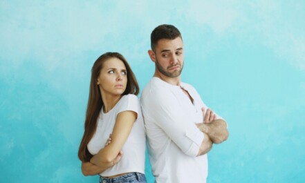 Couple standing back to back with arms crossed