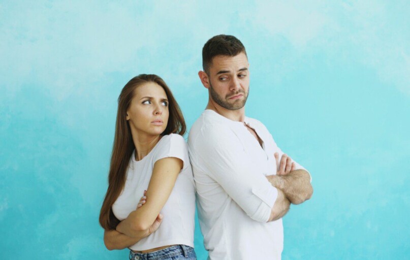 Couple standing back to back with arms crossed