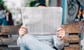 man sitting on bench reading newspaper