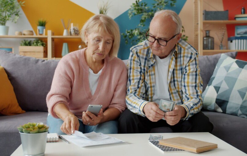 Elderly couple looking at bills and phone