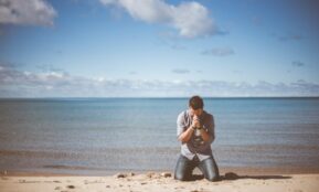 man kneeling down near shore