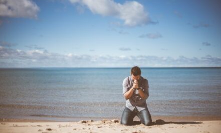man kneeling down near shore