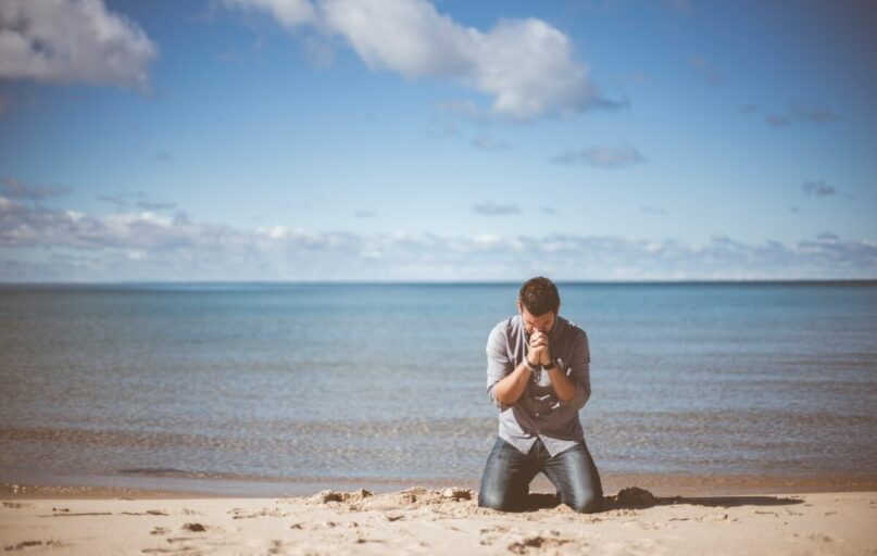 man kneeling down near shore