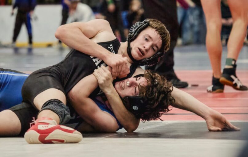 Two young men wrestling on a mat