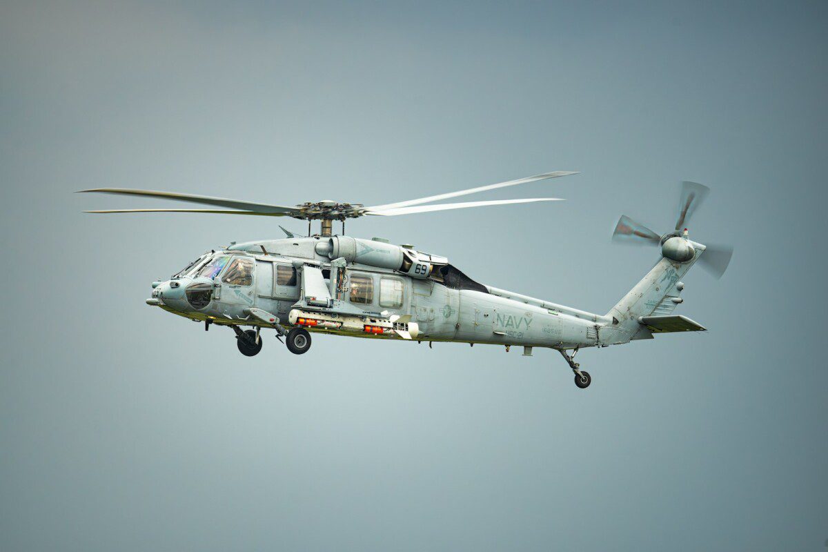 A military helicopter flies in the sky.