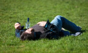 a man laying in the grass with a bottle of beer