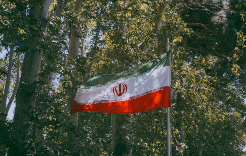 Iranian flag waving amidst green trees