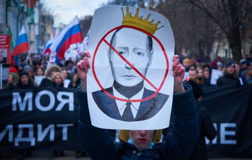 man in blue jacket holding white and red bird print banner