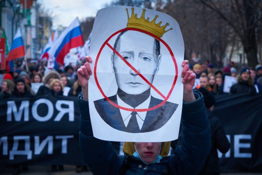 man in blue jacket holding white and red bird print banner