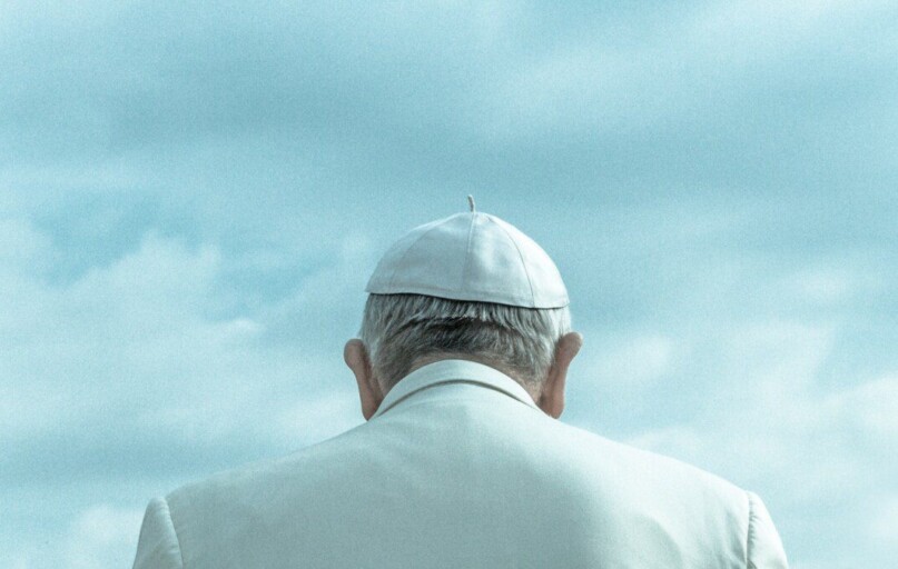 person wearing white cap looking down under cloudy sky during daytime