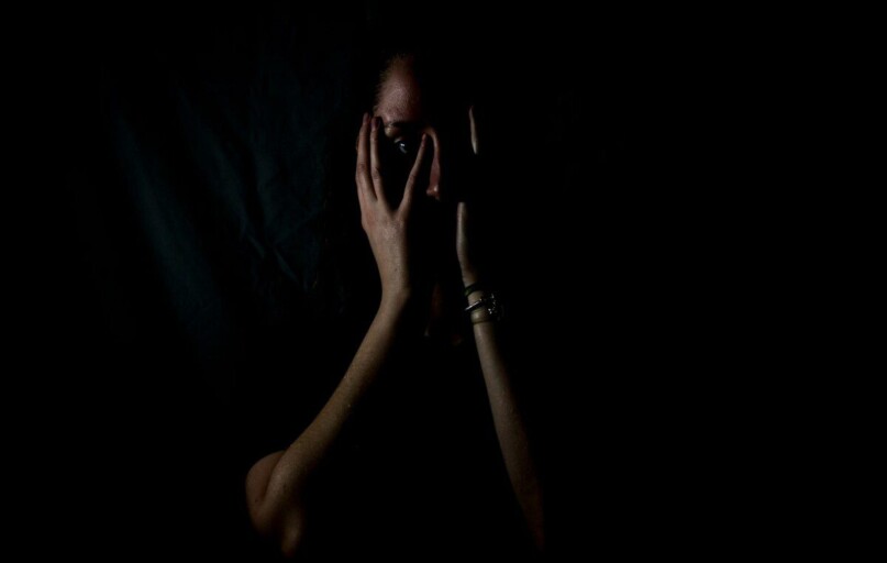 woman holding her face in dark room