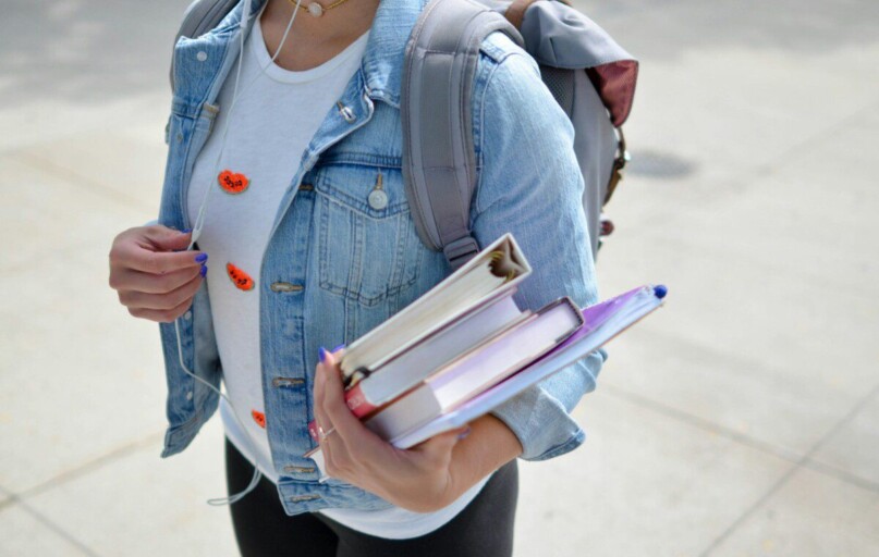 woman wearing blue denim jacket holding book