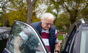 Elderly man getting into a car