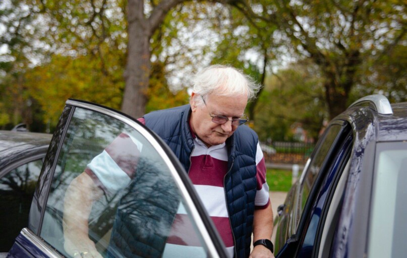 Elderly man getting into a car