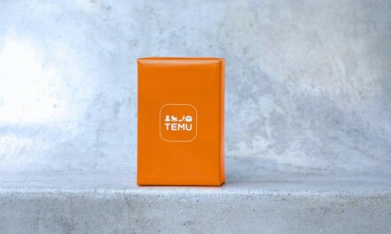 Orange box with white logo on concrete surface.