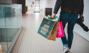 person walking while carrying a camera and paper bags