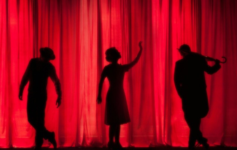 silhouette of three performers on stage