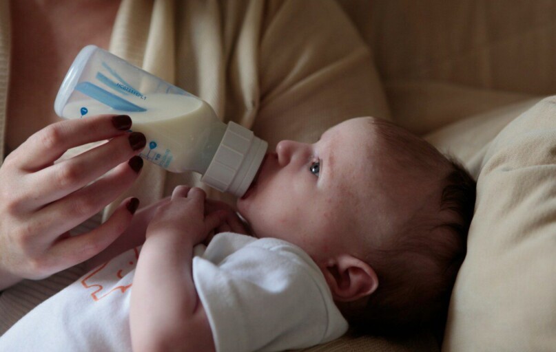 a woman feeding a baby with a bottle of milk