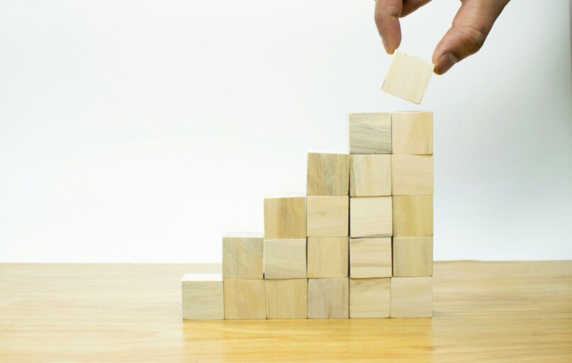 A person placing a piece of wood into a pyramid