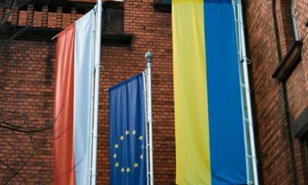a brick building with three flags hanging from it's sides