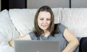 a woman sitting on a couch using a laptop computer