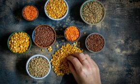 a person touching a bowl of lentils on a table