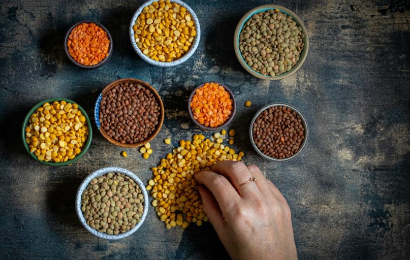 a person touching a bowl of lentils on a table