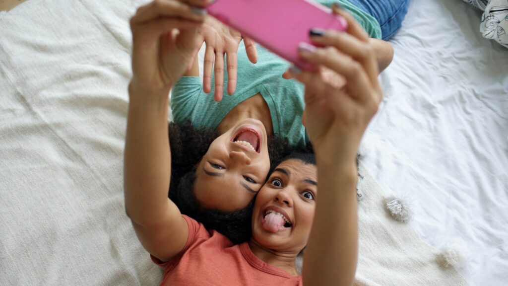 Two friends taking a selfie on a bed