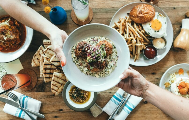 person holding white plate with food