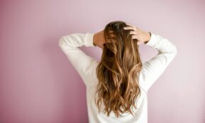 woman in white long-sleeved shirt standing in front of pink wall