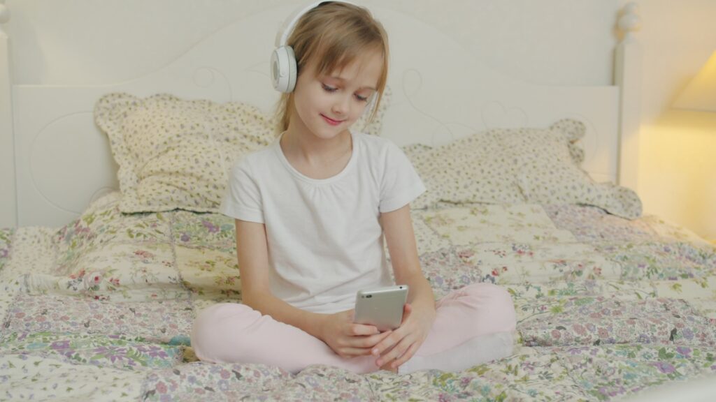 A young girl listens to music on her phone.