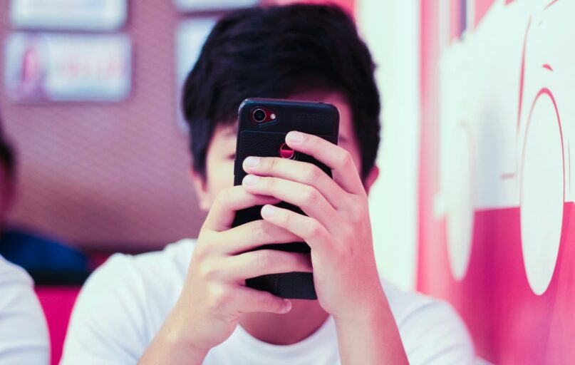 man in white crew neck t-shirt holding black iphone 5