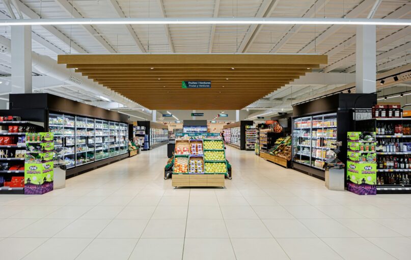 A brightly lit supermarket aisle with shelves of products.