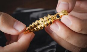 a person is holding a gold chain with a clasp on it