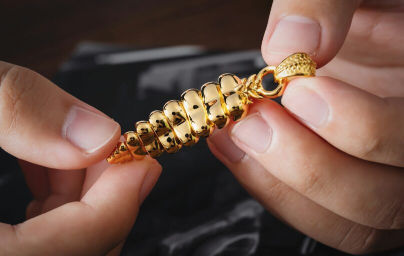 a person is holding a gold chain with a clasp on it