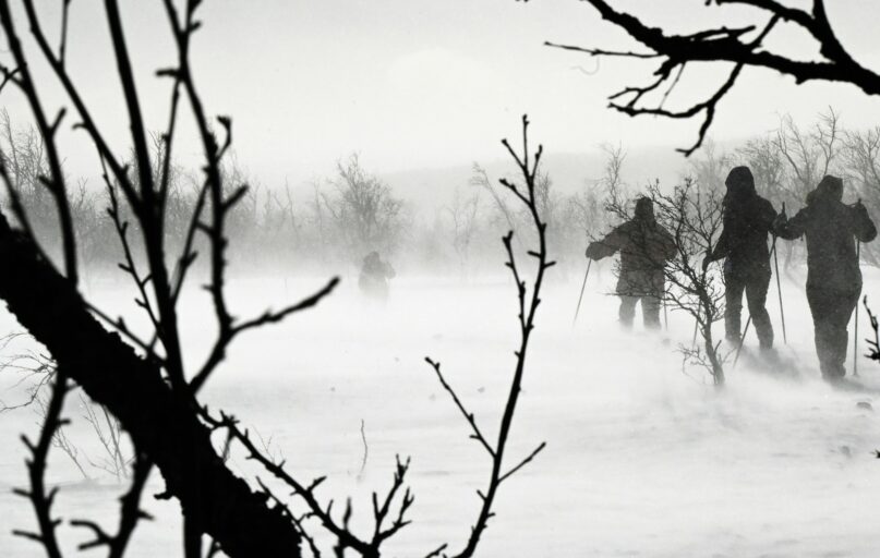 a group of people walking across a snow covered field
