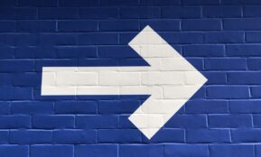white arrow painted on brick wall