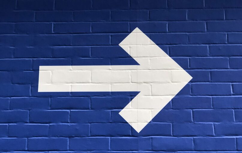 white arrow painted on brick wall