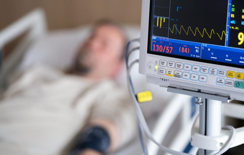 a man laying in a hospital bed next to a monitor