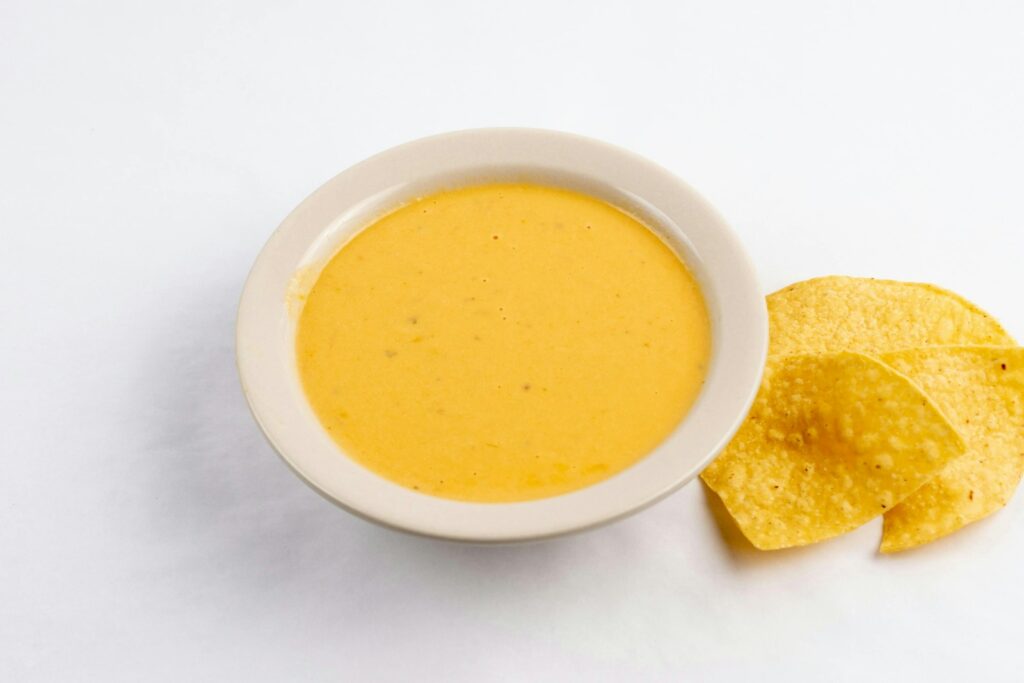 A bowl of soup next to some chips