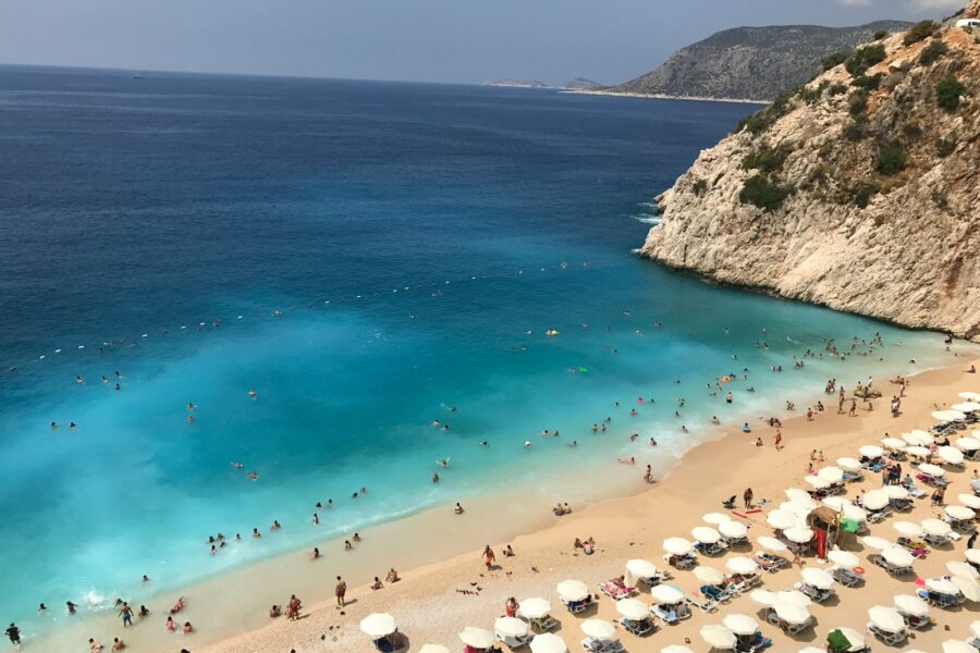 high angle photo of people gathering on seashore near mountain cliff