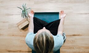 woman in black shirt and gray pants sitting on brown wooden bench