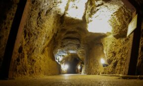 Illuminated pathway through a rough-hewn mine tunnel