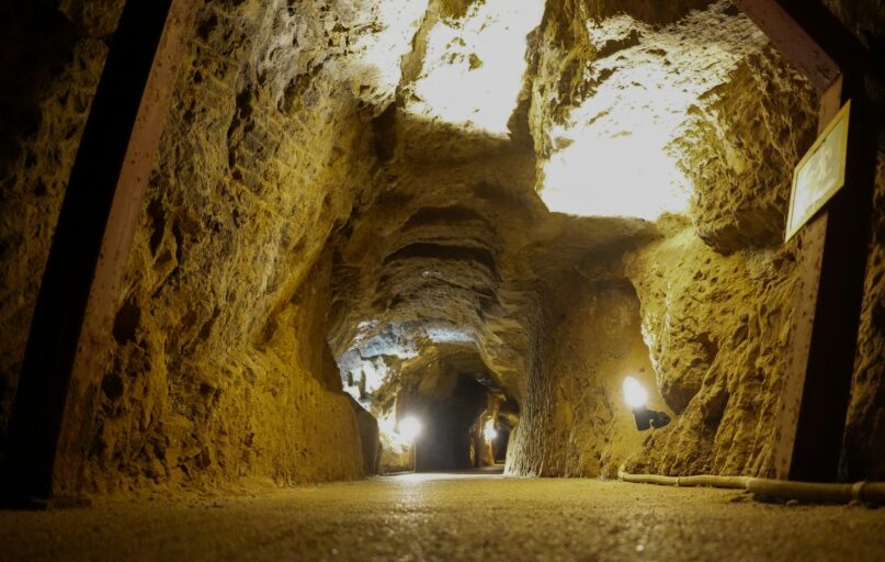 Illuminated pathway through a rough-hewn mine tunnel