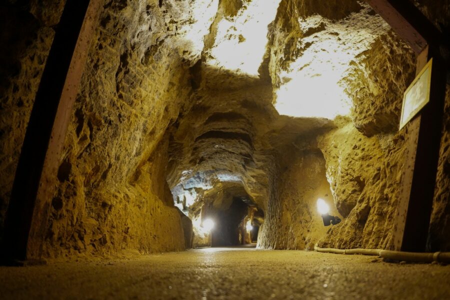 Illuminated pathway through a rough-hewn mine tunnel