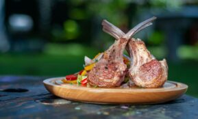 a wooden plate topped with meat and vegetables