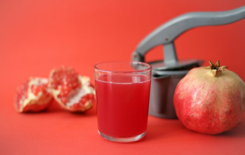 clear drinking glass with red liquid beside red apple fruit