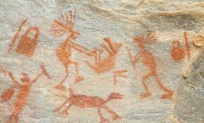 a rock painting of people and animals on it