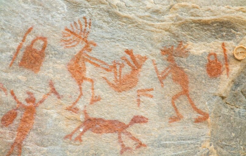 a rock painting of people and animals on it